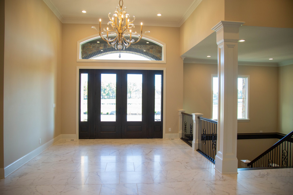 This is an example of an expansive classic foyer in Indianapolis with yellow walls, marble flooring, a double front door, a dark wood front door and white floors.