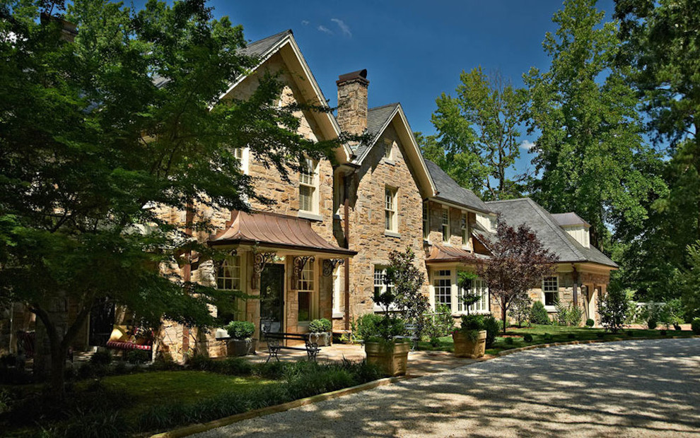 Photo of a mid-sized traditional two-storey beige house exterior in Charlotte with stone veneer, a clipped gable roof and a shingle roof.