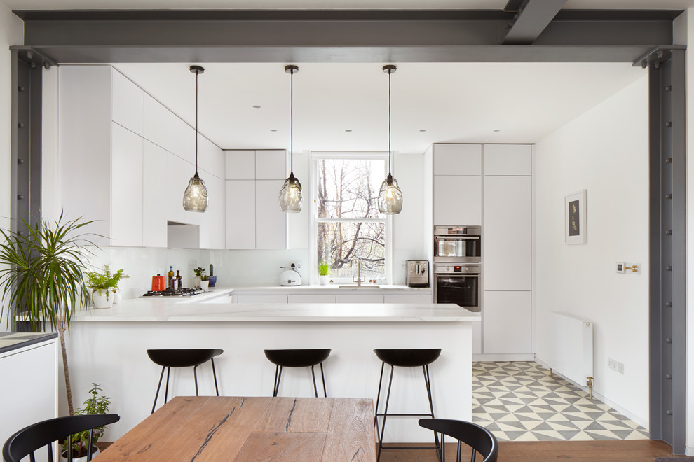 Inspiration for a large contemporary eat-in kitchen in London with dark hardwood floors, flat-panel cabinets, white cabinets and stainless steel appliances.