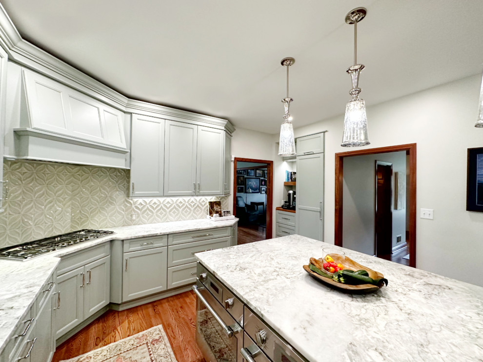 Example of a transitional l-shaped medium tone wood floor eat-in kitchen design with shaker cabinets, green cabinets, quartzite countertops, porcelain backsplash, paneled appliances and an island