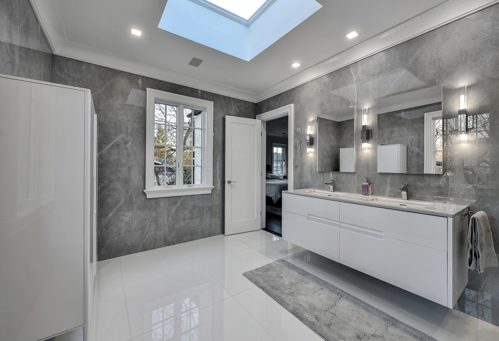 This is an example of a large modern master bathroom in New York with flat-panel cabinets, white cabinets, a curbless shower, a bidet, gray tile, porcelain tile, grey walls, marble floors, an integrated sink, marble benchtops, white floor, a hinged shower door, grey benchtops, a shower seat, a double vanity, a floating vanity and coffered.