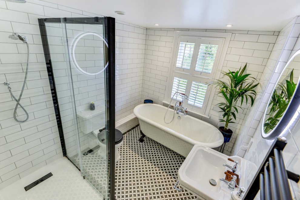 Mid-sized traditional kids bathroom in Sussex with a freestanding tub, a corner shower, a two-piece toilet, white tile, ceramic tile, white walls, ceramic floors, a pedestal sink, tile benchtops, multi-coloured floor, a sliding shower screen, black benchtops and a single vanity.