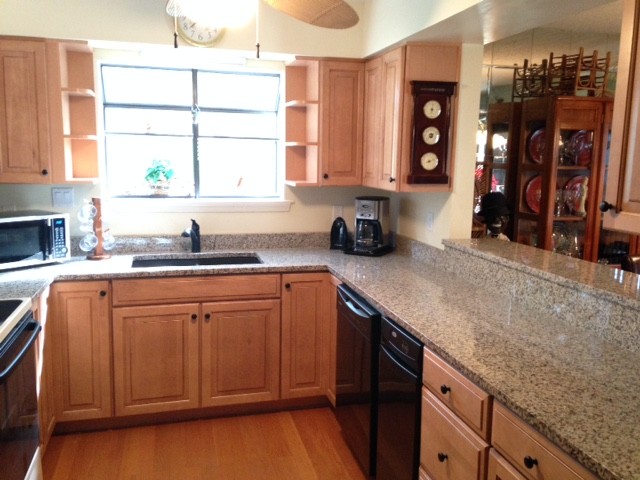 Inspiration for a small transitional u-shaped medium tone wood floor enclosed kitchen remodel with an undermount sink, raised-panel cabinets, medium tone wood cabinets, granite countertops, black appliances and no island