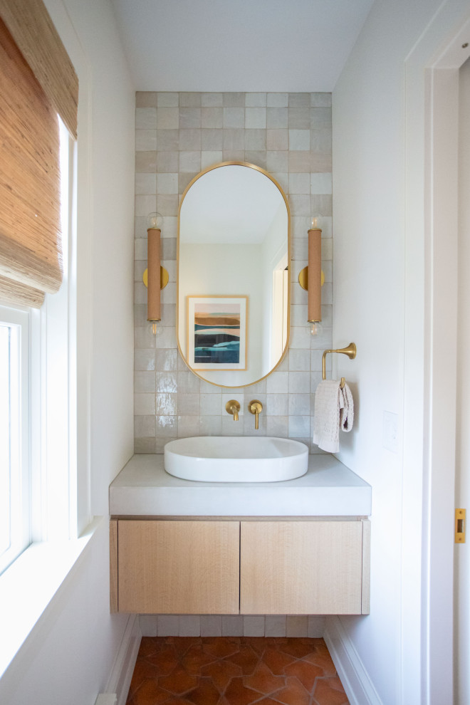 Example of a small beach style gray tile and stone tile terra-cotta tile and brown floor powder room design in Minneapolis with flat-panel cabinets, light wood cabinets, a two-piece toilet, white walls, a vessel sink, concrete countertops, gray countertops and a floating vanity