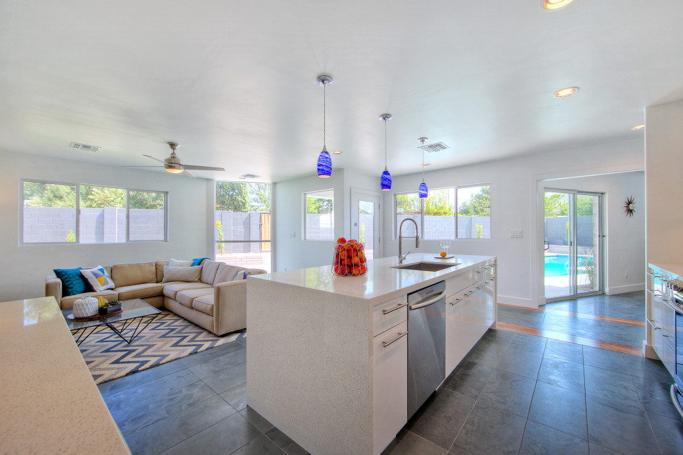 Photo of a contemporary l-shaped open plan kitchen in Phoenix with an undermount sink, flat-panel cabinets, white cabinets, quartz benchtops, white splashback, glass tile splashback, stainless steel appliances, slate floors, with island, black floor and white benchtop.