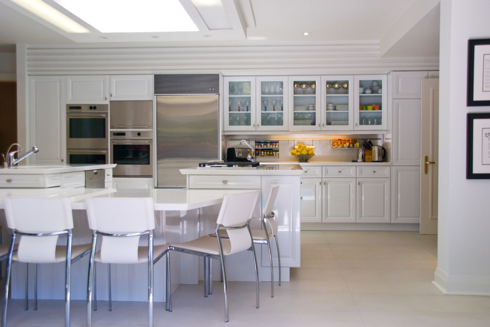 Eat-in kitchen - large transitional u-shaped marble floor eat-in kitchen idea in Toronto with a single-bowl sink, raised-panel cabinets, white cabinets, solid surface countertops, stainless steel appliances and a peninsula