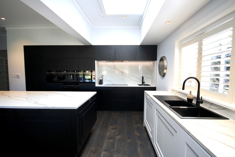 Inspiration for an expansive modern l-shaped eat-in kitchen in Sydney with a drop-in sink, raised-panel cabinets, black cabinets, quartz benchtops, white splashback, stone slab splashback, black appliances, dark hardwood floors, multiple islands, black floor and white benchtop.