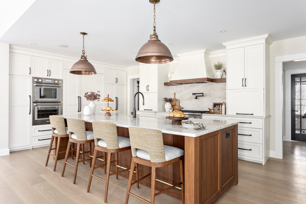 Example of a large transitional l-shaped medium tone wood floor and brown floor open concept kitchen design in Other with an undermount sink, shaker cabinets, quartz countertops, multicolored backsplash, quartz backsplash, stainless steel appliances, an island, beige countertops and white cabinets
