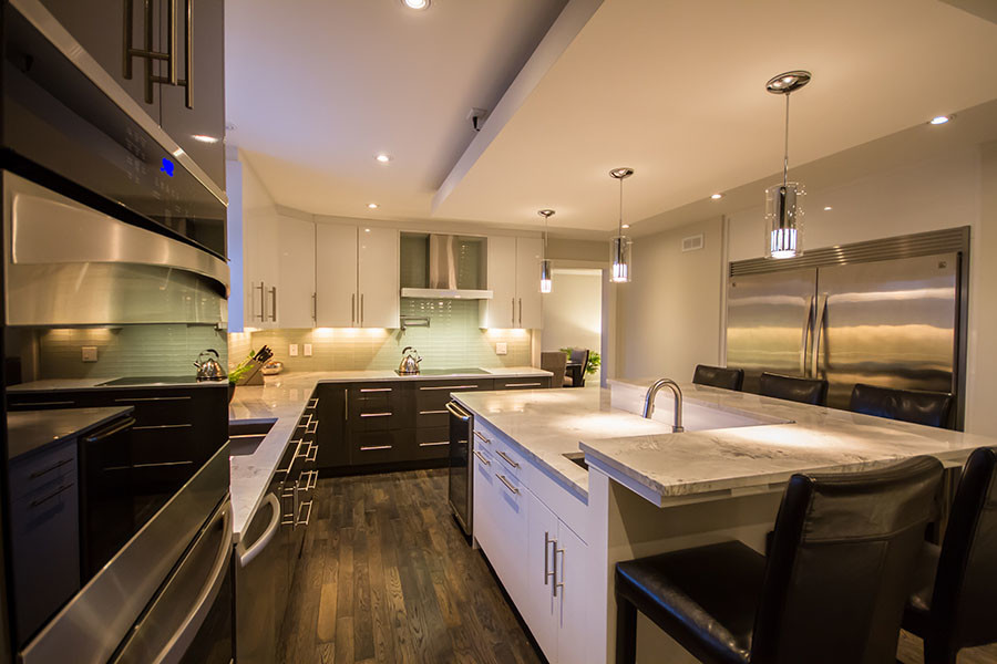 Open concept kitchen - large transitional l-shaped dark wood floor open concept kitchen idea with an undermount sink, flat-panel cabinets, white cabinets, granite countertops, green backsplash, glass tile backsplash, stainless steel appliances and an island