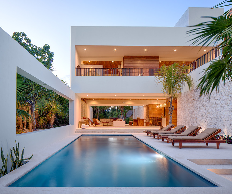 Inspiration for a mid-sized tropical backyard rectangular lap pool in Other with a pool house.