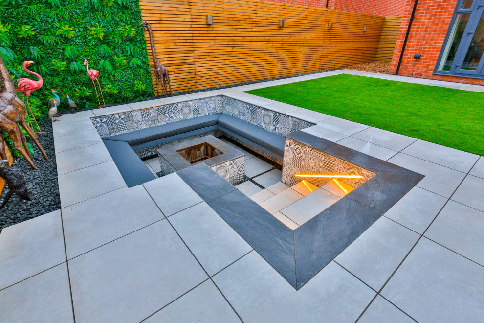 Inspiration for a modern backyard garden in Buckinghamshire with a fire feature and a wood fence.
