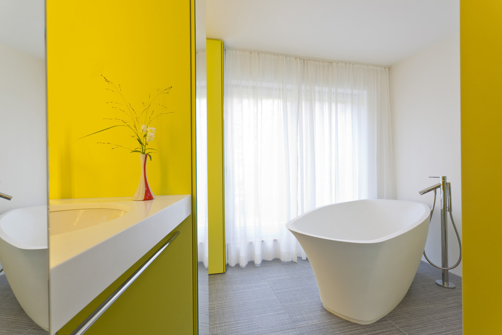Design ideas for a small contemporary bathroom in Frankfurt with a wall-mount sink, a freestanding tub, a curbless shower, yellow walls, porcelain floors and yellow cabinets.