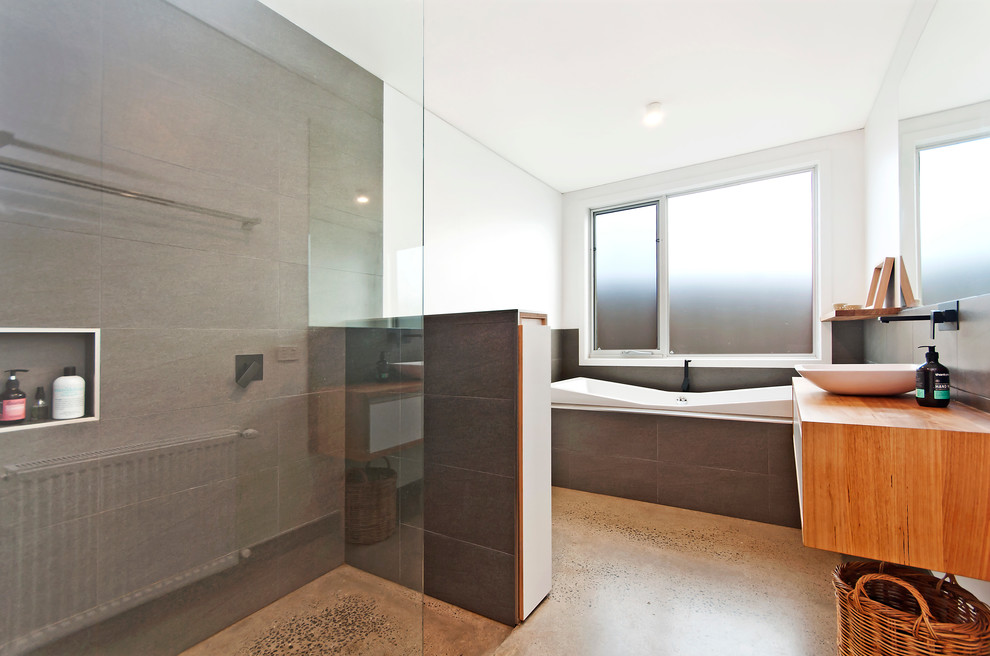 Design ideas for a mid-sized contemporary master bathroom in Geelong with wood benchtops, gray tile, ceramic tile, a drop-in tub, an open shower, a one-piece toilet, a vessel sink, white walls, concrete floors, furniture-like cabinets, medium wood cabinets and an open shower.