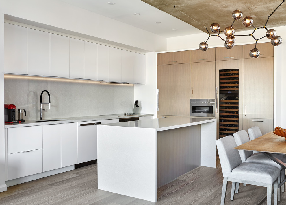 Design ideas for a large contemporary l-shaped eat-in kitchen in Toronto with an undermount sink, flat-panel cabinets, white cabinets, quartz benchtops, grey splashback, stone slab splashback, panelled appliances, medium hardwood floors, with island, brown floor and white benchtop.