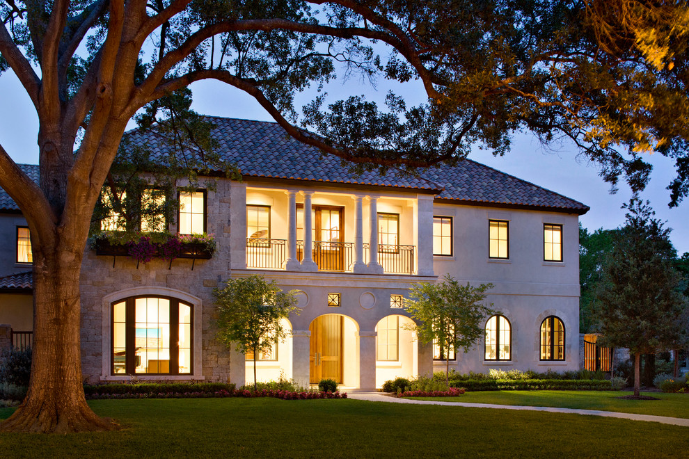 This is an example of a large mediterranean two-storey beige exterior in Houston with stone veneer and a hip roof.