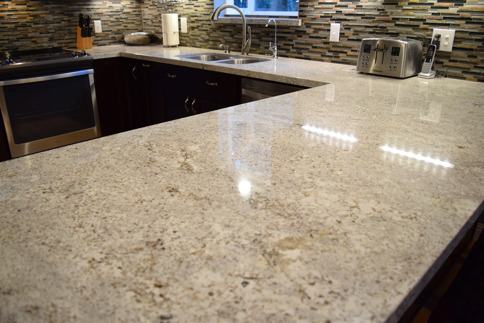 Example of a mid-sized mountain style u-shaped eat-in kitchen design with an undermount sink, recessed-panel cabinets, dark wood cabinets, granite countertops, multicolored backsplash, stainless steel appliances and a peninsula