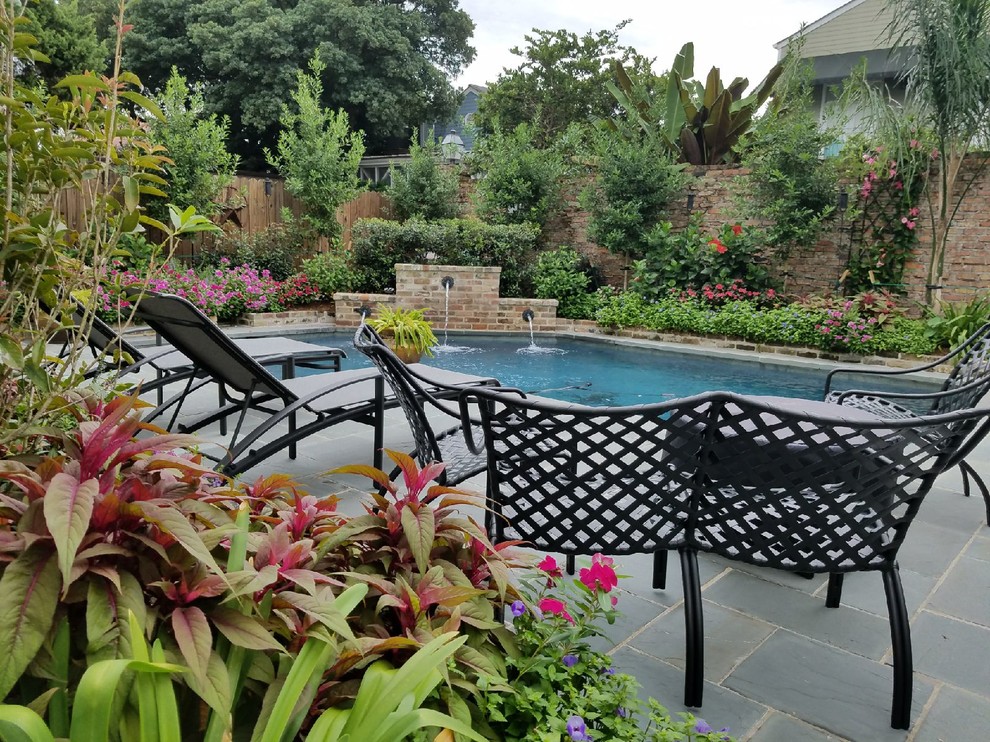 Photo of a traditional backyard pool in New Orleans with a water feature and natural stone pavers.