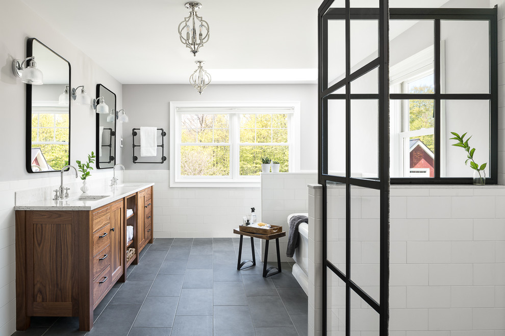 Design ideas for a mid-sized beach style master bathroom in Burlington with medium wood cabinets, a freestanding tub, a bidet, white tile, ceramic tile, porcelain floors, an undermount sink, grey floor, a sliding shower screen, multi-coloured benchtops and flat-panel cabinets.