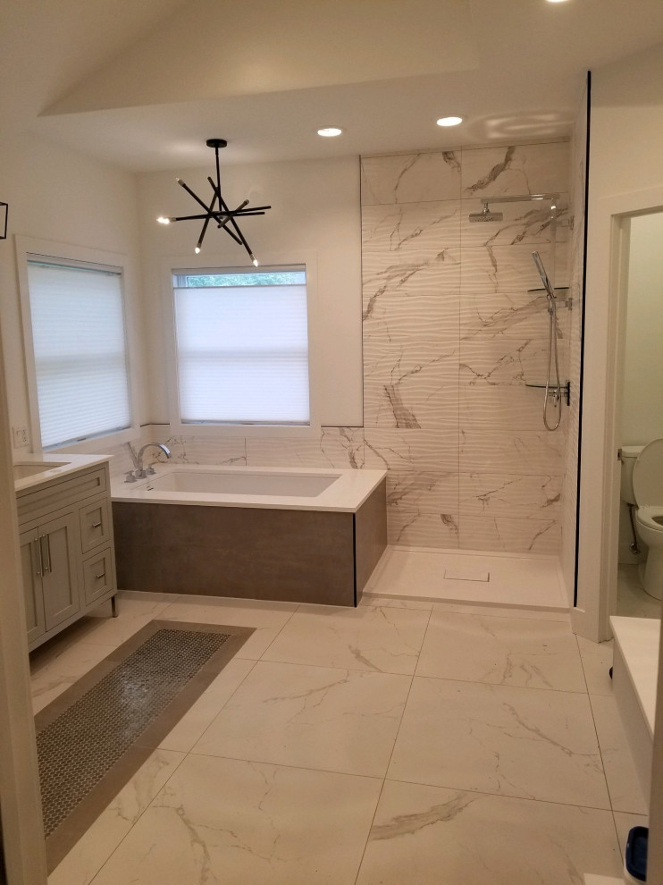 Photo of a mid-sized modern master bathroom in Chicago with recessed-panel cabinets, grey cabinets, an undermount tub, a corner shower, black and white tile, porcelain tile, white walls, porcelain floors, an undermount sink, engineered quartz benchtops, white floor, an open shower, white benchtops, an enclosed toilet, a double vanity and a freestanding vanity.