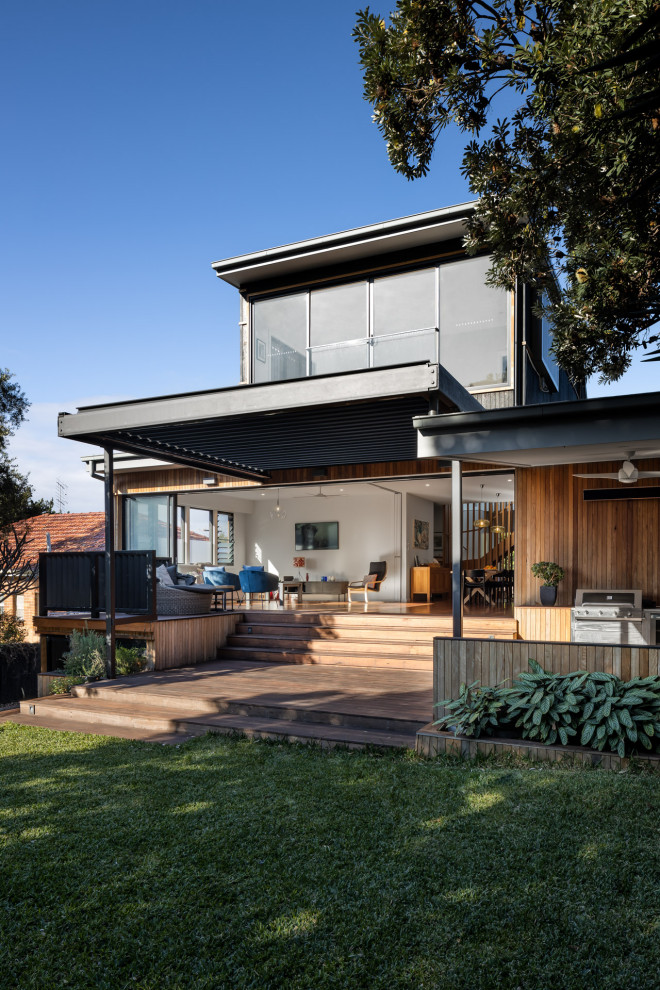 Mid-sized contemporary backyard deck in Sydney with with privacy feature and a pergola.