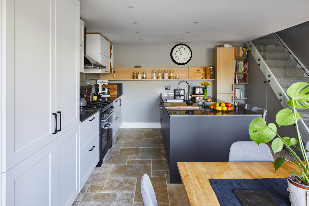 Photo of a mid-sized transitional single-wall eat-in kitchen in London with shaker cabinets, white cabinets, quartz benchtops, grey splashback, stone slab splashback, with island and grey benchtop.