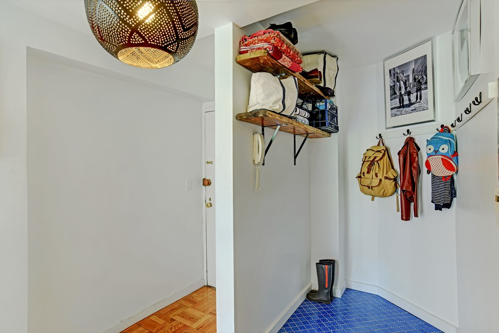 This is an example of a small mediterranean mudroom in New York with white walls, porcelain floors, a white front door, blue floor and a single front door.