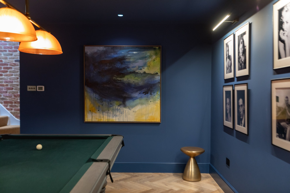 Photo of a large contemporary fully buried basement in London with blue walls, medium hardwood floors, no fireplace and brown floor.