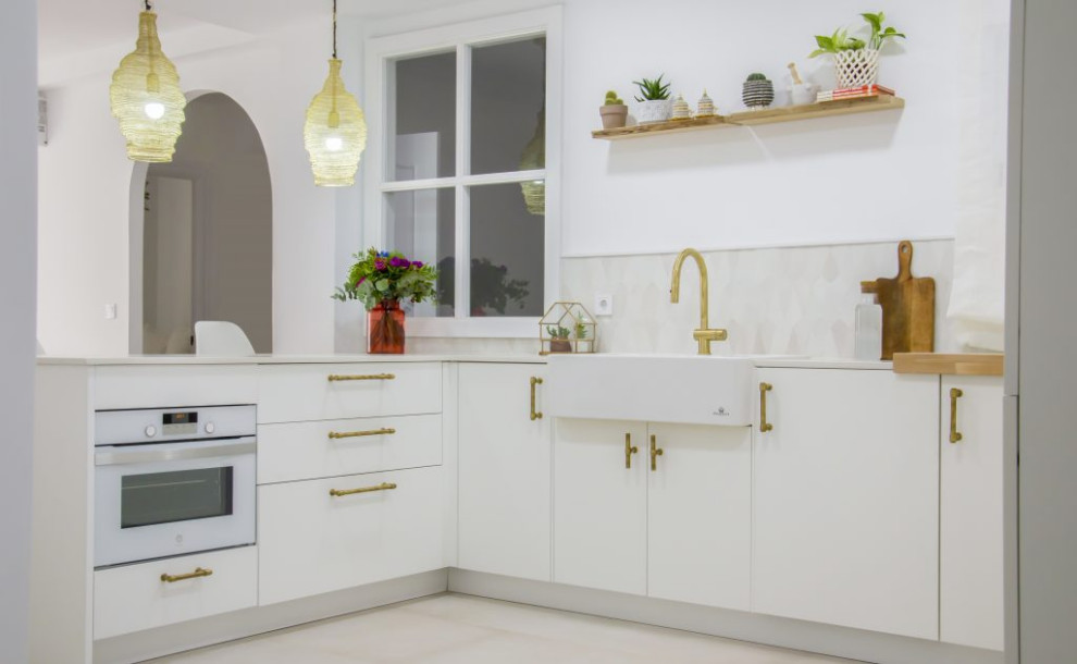 Inspiration for a mid-sized eclectic u-shaped open plan kitchen in Malaga with a farmhouse sink, white cabinets, white appliances, a peninsula and white floor.