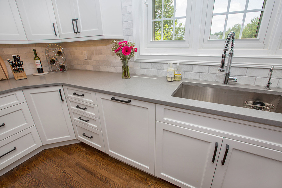 This is an example of a mid-sized traditional l-shaped separate kitchen in Cincinnati with an undermount sink, shaker cabinets, white cabinets, quartz benchtops, grey splashback, stone tile splashback, stainless steel appliances, medium hardwood floors, with island and brown floor.