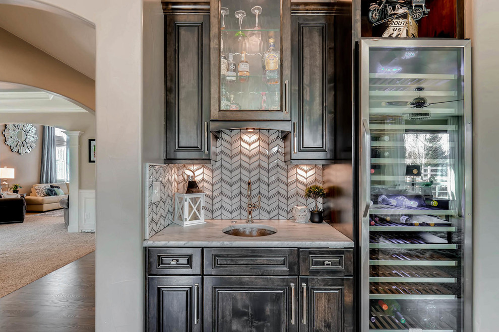 Small contemporary single-wall wet bar in Denver with an undermount sink, louvered cabinets, dark wood cabinets, quartz benchtops, white splashback, glass tile splashback, medium hardwood floors, brown floor and white benchtop.