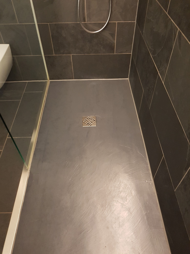 Inspiration för mellanstora moderna grått badrum med dusch, med öppna hyllor, grå skåp, en kantlös dusch, en toalettstol med separat cisternkåpa, grå kakel, skifferkakel, grå väggar, skiffergolv, ett fristående handfat, bänkskiva i glas, grått golv och med dusch som är öppen