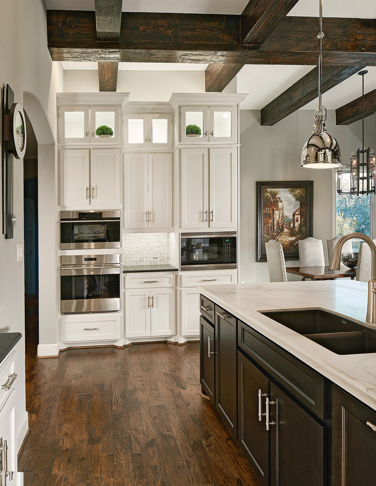 This is an example of an expansive transitional kitchen in Dallas with stainless steel appliances, dark hardwood floors, with island, recessed-panel cabinets, white cabinets and marble benchtops.