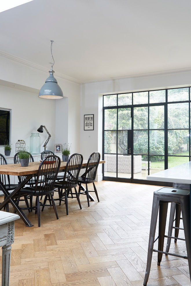 This is an example of a contemporary dining room in London with white walls, light hardwood floors and beige floor.