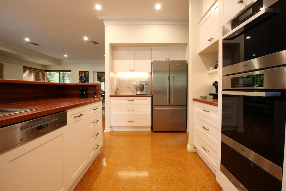 Photo of a large traditional u-shaped open plan kitchen in Perth with shaker cabinets, white cabinets, wood benchtops and stainless steel appliances.