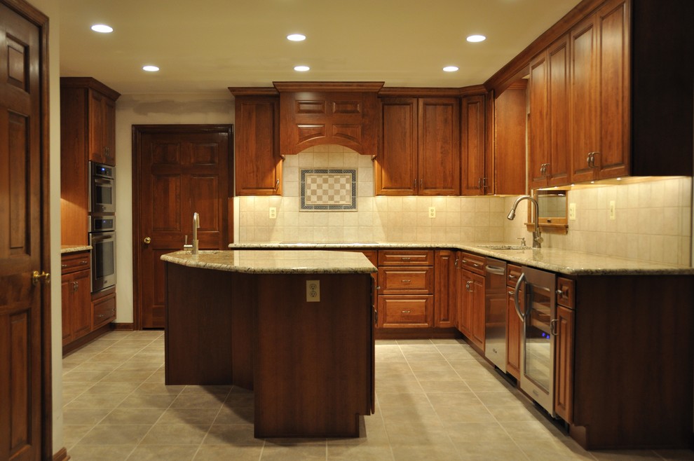 Photo of a mid-sized traditional u-shaped separate kitchen in Baltimore with an undermount sink, medium wood cabinets, granite benchtops, beige splashback, ceramic splashback, stainless steel appliances, ceramic floors, beige floor, multi-coloured benchtop, raised-panel cabinets and with island.