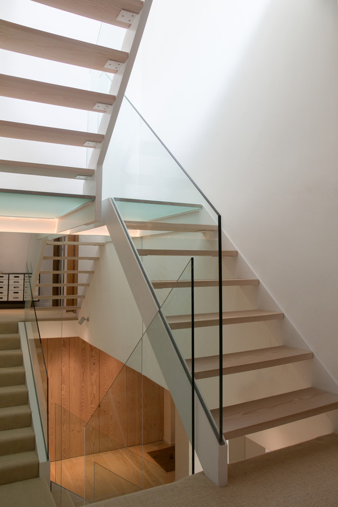 Mid-sized contemporary wood u-shaped staircase in London with open risers.