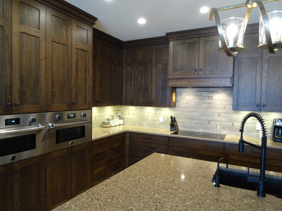 Inspiration for a large transitional l-shaped light wood floor and brown floor kitchen pantry remodel with an undermount sink, shaker cabinets, medium tone wood cabinets, granite countertops, gray backsplash, stone tile backsplash, stainless steel appliances, an island and multicolored countertops