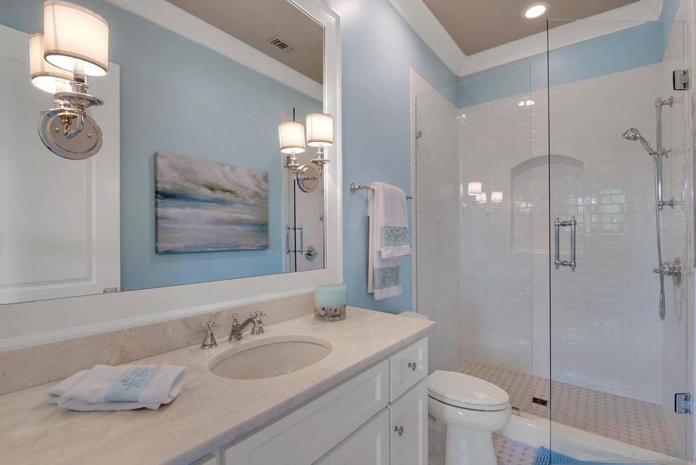 Photo of a large country bathroom in Other with recessed-panel cabinets, white cabinets, an alcove shower, a one-piece toilet, multi-coloured tile, ceramic tile, white walls, linoleum floors, an undermount sink and marble benchtops.