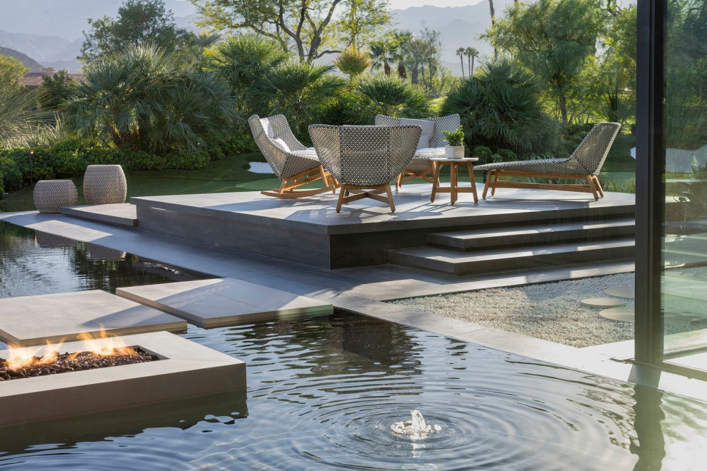 Example of a huge minimalist backyard tile patio design in Los Angeles with a fire pit and a roof extension