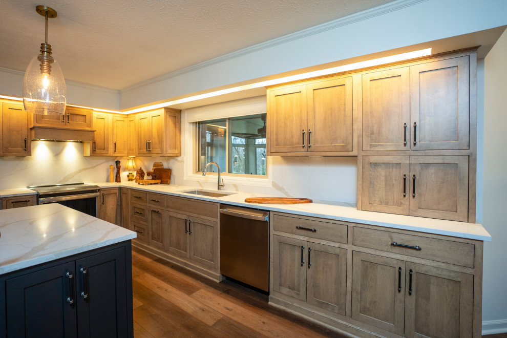 Example of a large transitional l-shaped medium tone wood floor and brown floor eat-in kitchen design with a single-bowl sink, shaker cabinets, medium tone wood cabinets, quartz countertops, white backsplash, quartz backsplash, stainless steel appliances, an island and white countertops
