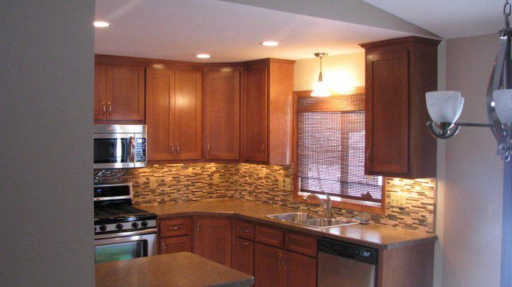 Eat-in kitchen - mid-sized traditional l-shaped porcelain tile eat-in kitchen idea in Minneapolis with a double-bowl sink, recessed-panel cabinets, medium tone wood cabinets, laminate countertops, multicolored backsplash, glass sheet backsplash, stainless steel appliances and a peninsula