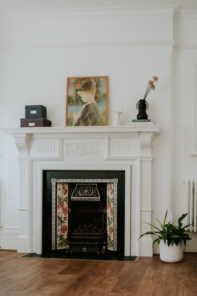 Inspiration pour un salon traditionnel de taille moyenne et fermé avec un mur blanc, un sol en vinyl, un manteau de cheminée en bois, un téléviseur indépendant et un sol marron.