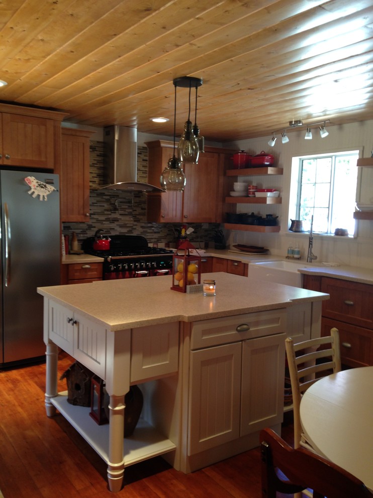 Inspiration for a mid-sized rustic l-shaped medium tone wood floor open concept kitchen remodel with a farmhouse sink, beaded inset cabinets, light wood cabinets, solid surface countertops, beige backsplash, glass tile backsplash, stainless steel appliances and an island