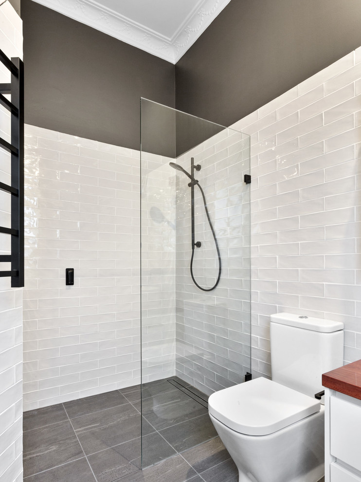 Photo of a mid-sized contemporary master bathroom in Perth with a one-piece toilet, black and white tile, subway tile, ceramic floors, a vessel sink, wood benchtops, an open shower, white walls and black floor.