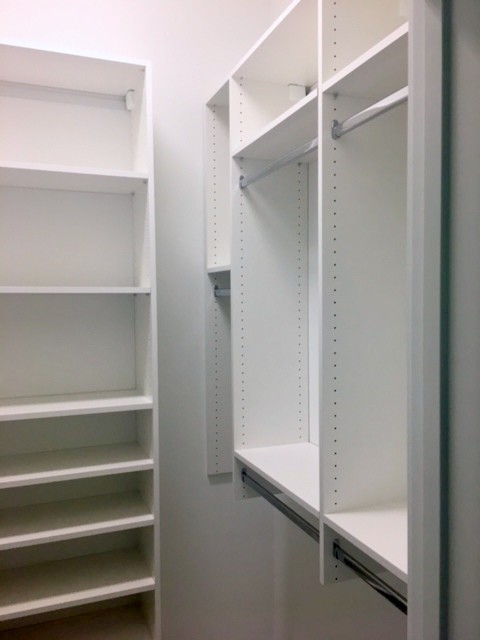This is an example of a small modern gender-neutral walk-in wardrobe in Other with white cabinets.