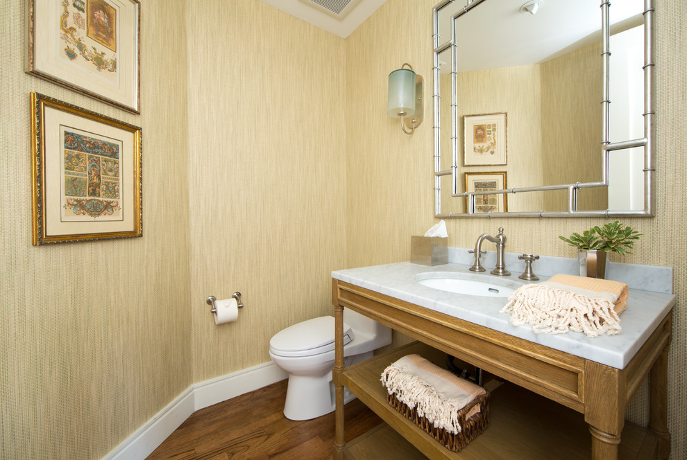 Photo of a small transitional powder room in Los Angeles with open cabinets, light wood cabinets, a one-piece toilet, yellow tile, yellow walls, medium hardwood floors, an undermount sink, marble benchtops and brown floor.