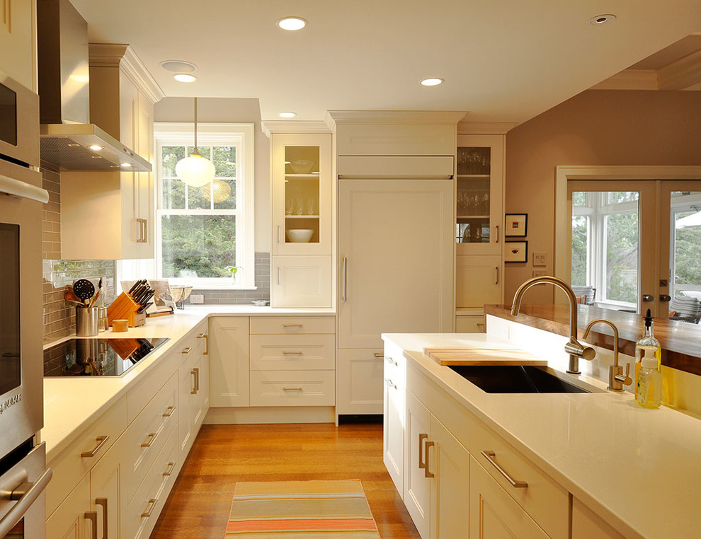 Example of a mid-sized u-shaped medium tone wood floor kitchen design in Boston with a drop-in sink, shaker cabinets, white cabinets, quartzite countertops, gray backsplash, subway tile backsplash, stainless steel appliances and an island