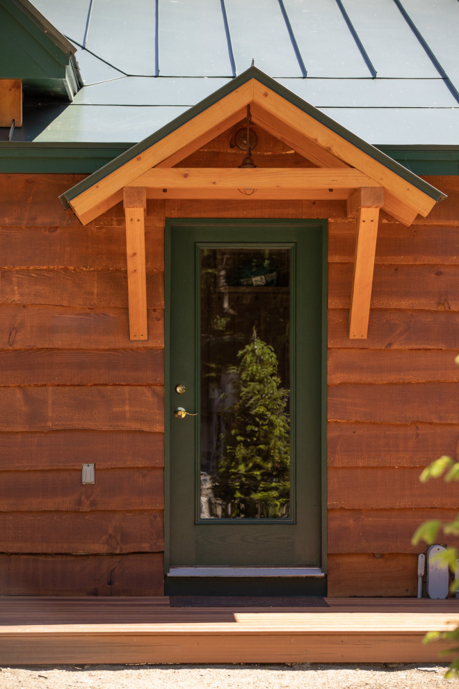 На фото: двухэтажный, деревянный, коричневый частный загородный дом в стиле рустика с металлической крышей, отделкой планкеном и двускатной крышей с
