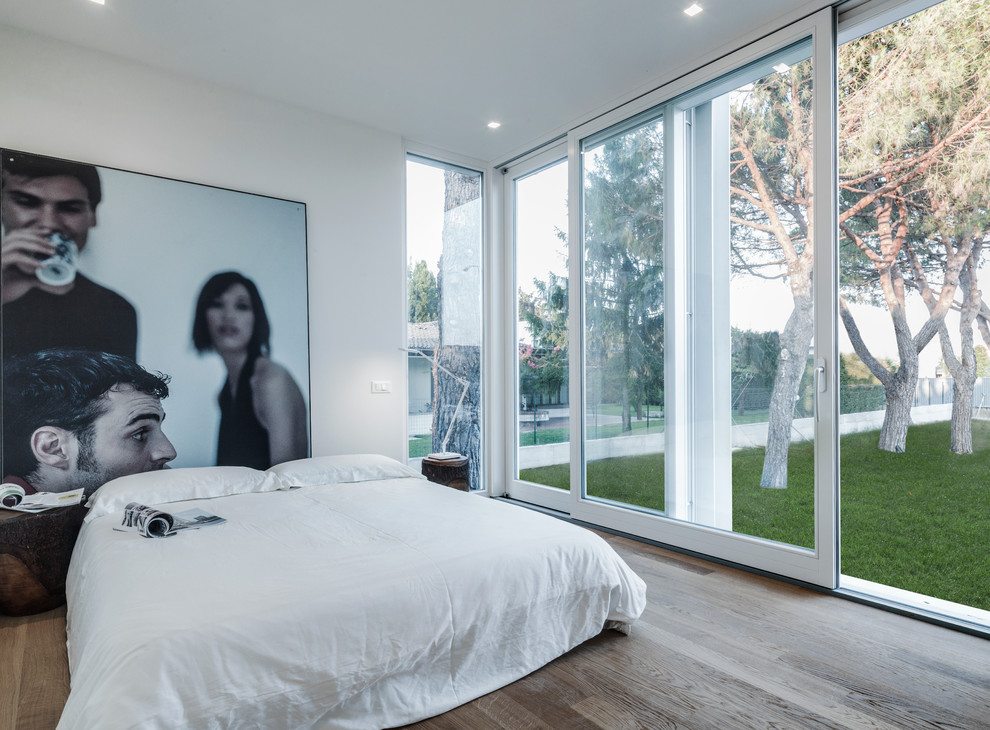 Mid-sized contemporary master bedroom in Other with white walls and light hardwood floors.