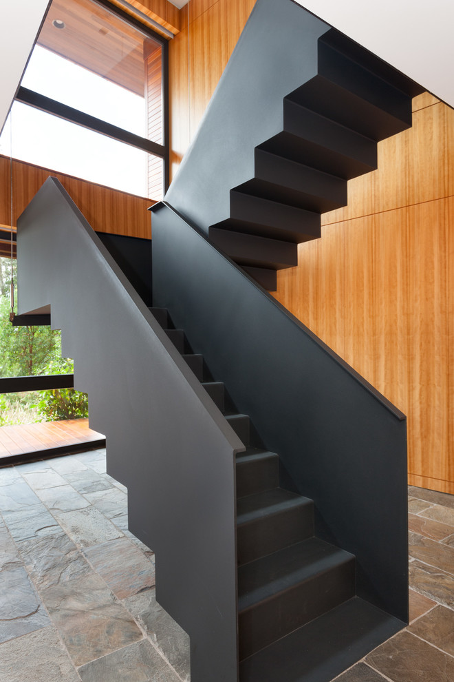 Large contemporary metal u-shaped staircase in Vancouver with metal risers and metal railing.